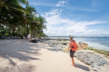 Hobby and vacation. Young man with surfboard on beautiful tropical beach.