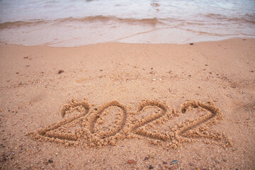 the inscription 2022 in the sand and wave of the sea