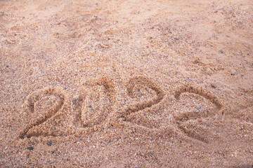 the inscription 2022 in the sand and wave of the sea