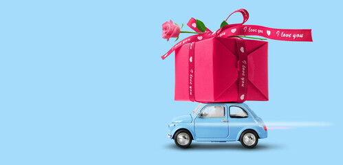 Blue toy car with gift box on a roof and rose flower
