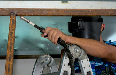 A man in a welding mask works with a welding machine on a ladder