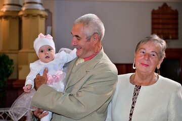 Portrait of old parent with granddaughter during baptism in church