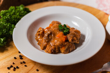 baked meat in slices in tomato red sauce in a white plate