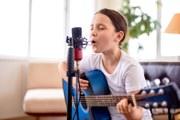 Play on. Talented child girl vocal artist singing in modern recording studio in order to create new...