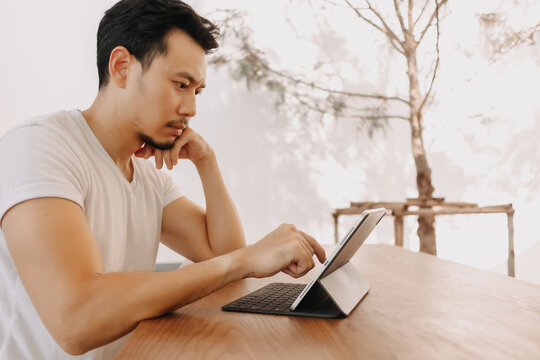 Freelance Asian man is working with concentrate on his tablet in the cafe.