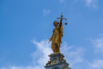 Fototapeta na wymiar Estatua de la Señora Justicia en la parte superior del Palacio de la Libertad ubicado en la Plaza Burg de Brujas, Bélgica. Personificación alegórica de la fuerza moral en los sistemas judiciales.