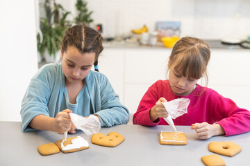 Portrait of happy small children decorating homemade cookies in kitchen and making xmas cookies together at home