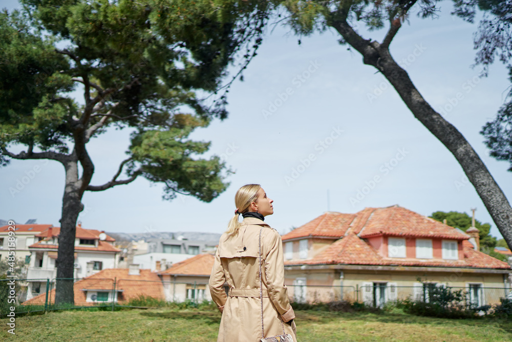 Wall mural Young traveling woman in coat  walking on Split Old Town park enjoying the view.