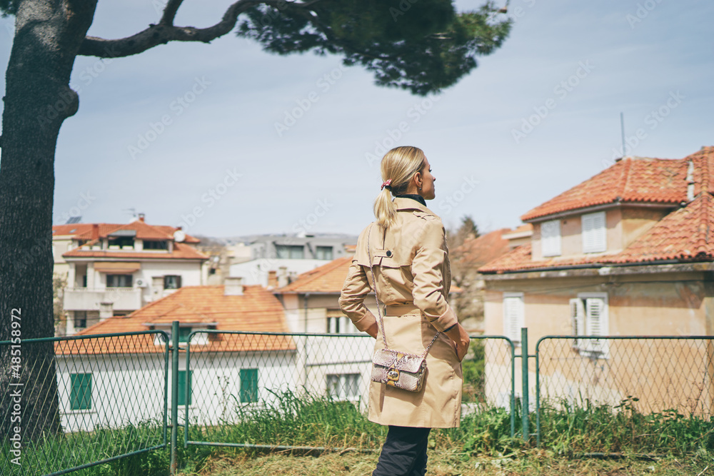 Wall mural Young traveling woman in coat  walking on Split Old Town park enjoying the view.