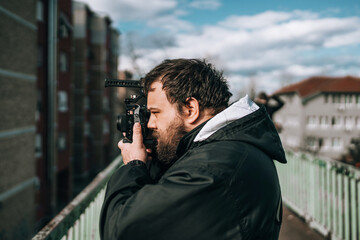 Young bearded hipster photographer taking some photos on the street