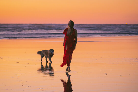 Female wearing a red dress on the Washington Coast at sunset
