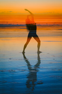 Abstract image of a nude female posing on the beach at sunset