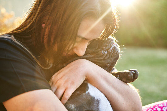 Young woman and her dog in the garden at sunset