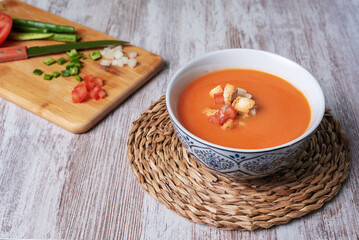 Gazpacho, cold soup typical of Andalusia based on tomato, garlic, pepper and onion. On a white wooden background.