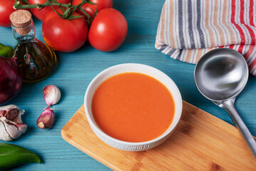 Gazpacho, cold soup typical of Andalusia based on tomato, garlic, pepper and onion. On a blue wooden background.