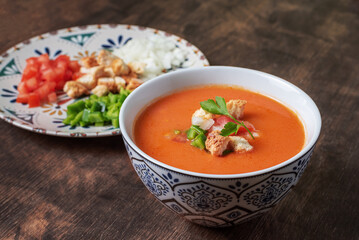 Gazpacho, typical Andalusian cold soup based on tomato, garlic, pepper and onion. On a dark wooden background.