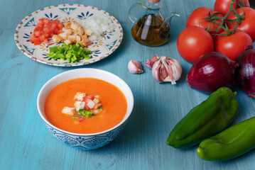 Gazpacho, cold soup typical of Andalusia based on tomato, garlic, pepper and onion. On a blue wooden background.