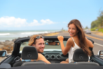 Road trip car rental travel happy people young tourists couple smiling at camera driving on summer...