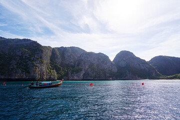 Fototapeta na wymiar Travel by Thailand. Beautiful tropical lanscape with traditional lontail boat sailing the sea with famous Maya Bay on the background.