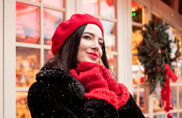 beautiful girl in a red beret and mittens in winter on New Year's street