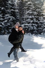 Fototapeta na wymiar Young couple on the snow in winter in the park. love and vacation concept - happy couple hugging and laughing outdoors in winter