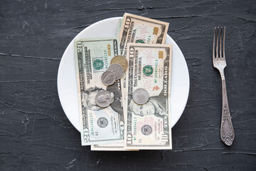 Money spend on food concept on black backgorund in the USA. Dollars in the plate. 