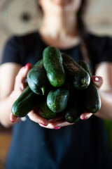 girl holding green cucumbers