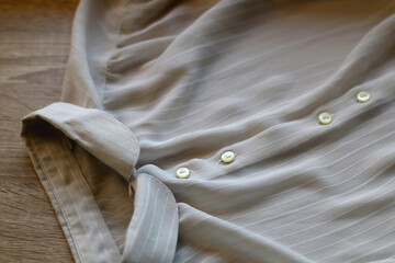 Gray striped blouse on wooden background. Selective focus.