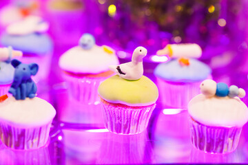 Candy bar, table with sweets, delicious sweet cupcakes lie on a glass plate on a table with lights