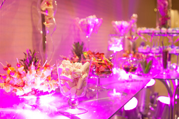 Candy bar, table with sweets, delicious sweet cupcakes lie on a glass plate on a table with lights