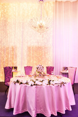 Table at a luxury wedding reception. Beautiful flowers on the table. Serving dishes, glass glasses, waiters work. Health and lifestyle