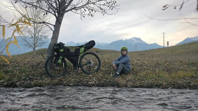 The woman travel on mixed terrain cycle touring with bikepacking. The traveler journey with bicycle bags. Sport tourism bikepacking.