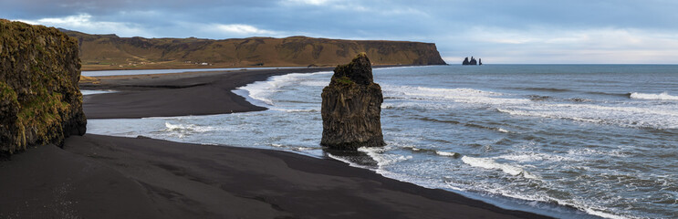 Picturesque autumn evening view to Reynisfjara ocean  black volcanic sand beach and rock formations from Dyrholaey Cape, Vik, South Iceland. Mount Reynisfjall on the background.