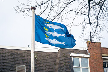 Blue flag of the fishing village of Scheveningen in The Netherlands with  three swimming herrings and crowns above their head