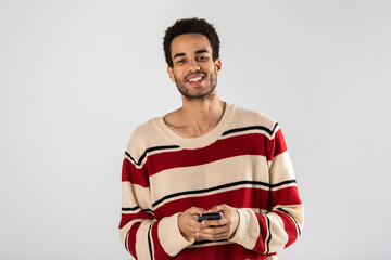 A young African American man with a smartphone in his hands stands on a white background.