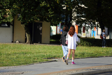 Dwie kobiety, dziewczyny z telefonem spacerują po chodniku, deptaku we Wrocławiu.	
