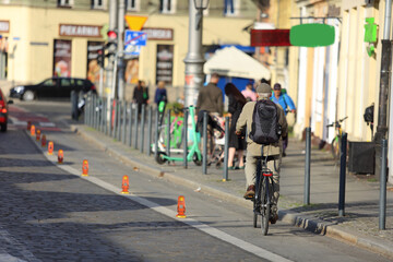 Starszy mężczyzna z plecakiem jedzie na rowerze ścieżką rowerową we Wrocławiu.	 - obrazy, fototapety, plakaty
