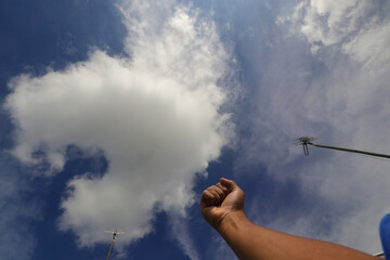 Fist facing clear blue sky with beautiful white clouds in daytime. The background concept of struggle, resistance, and searching for justice