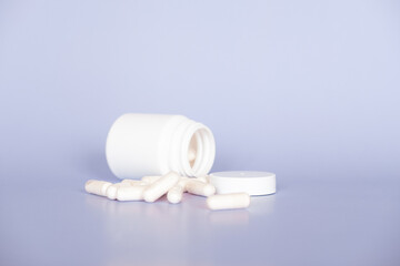 Close up white pills and capsules on purple background with copy space. Focus on foreground, soft bokeh. Pharmacy drugstore concept.