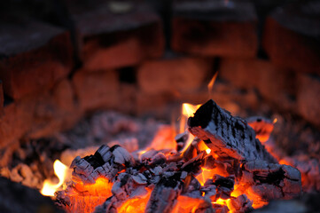 Glowing embers in hot red color, abstract background. The hot embers of burning wood log fire.