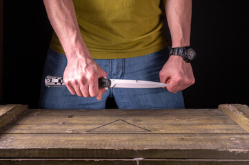 A large knife in the hands of a man. The man is holding a large knife. Sharp knife in hand.