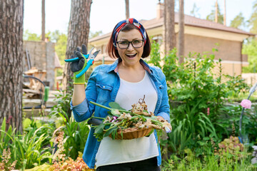 Outdoor portrait of a mature woman in a backyard garden tending flowerbeds.