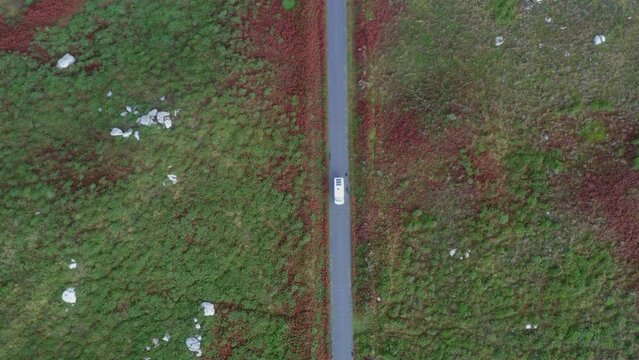 Drone aerial top view of camper van on a green and red landscape