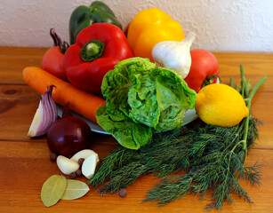 Obraz na płótnie Canvas Vegetables for a fresh salad. Pepper, lemon, tomatoes, garlic, carrots, onions and a lot of greens.