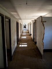 imagen de un pasillo con muchas puertas y la luz del sol entrando por la ventana en un edificio abandonado