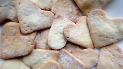 A full white plate of sweet homemade heart shaped cookies for the holiday