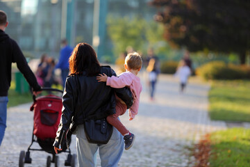 Kobieta z dzieckiem na ręku spaceruje w parku we Wrocławiu.
