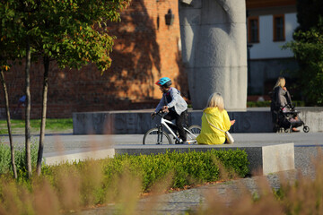 Kobieta wypoczywa, siedzi na betonowej ławce we Wrocławiu w parku. - obrazy, fototapety, plakaty