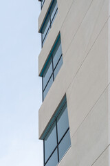 The exterior wall of a contemporary commercial style building with aluminum metal composite panels and glass windows. The futuristic building has engineered diagonal cladding steel frame panels.