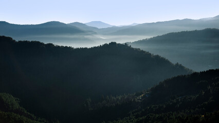 Montagnes dans la brume du soleil levant en hiver sur les forêts sauvages d'une vallée des Cévennes en France.